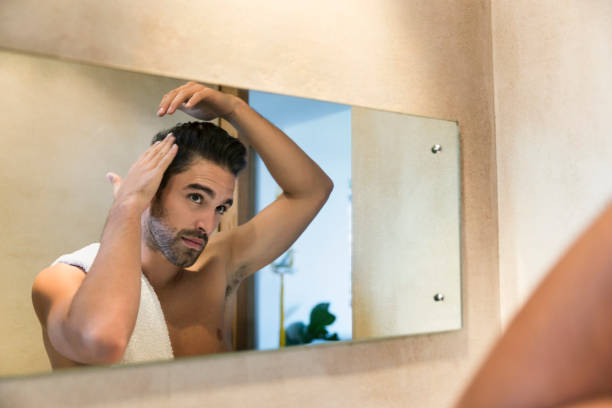 reflet dans le miroir du jeune homme fixant ses cheveux - male beauty beauty hairstyle shirtless photos et images de collection