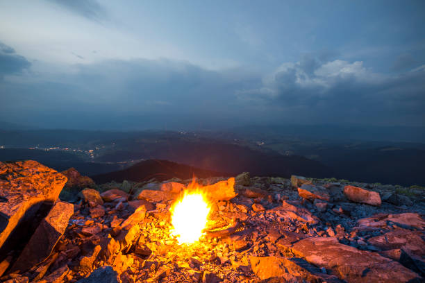 istock Beautiful summer night in mountain. Bright fire burns on rocky mountain top under blue cloudy sky. 1127524467