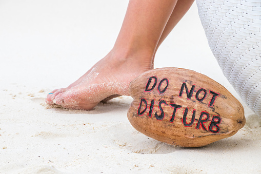 Woman feet on white sand and coconut with message