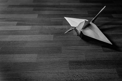 Un cisne de origami de papel sobre una mesa de madera en blanco y negro photo