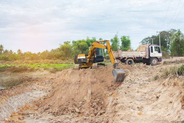 istock Yellow excavator machine loading soil into a dump truck at construction site 1127533172