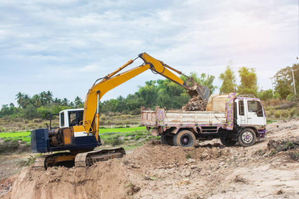 istock Yellow excavator machine loading soil into a dump truck at construction site 1127533560