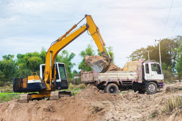 istock Yellow excavator machine loading soil into a dump truck at construction site 1127535438