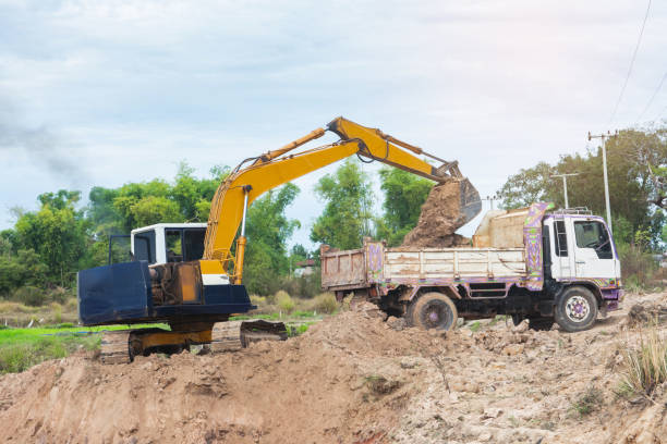 istock Yellow excavator machine loading soil into a dump truck at construction site 1127536000