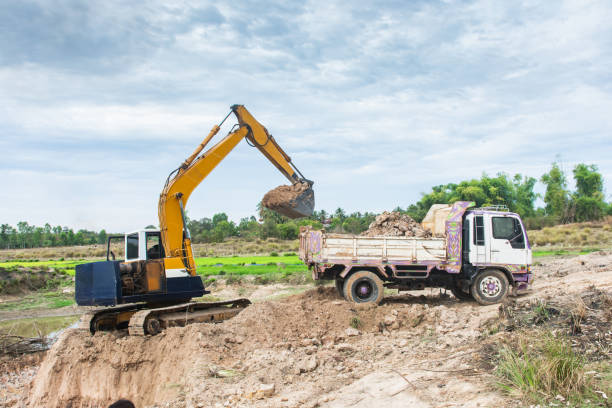 istock Yellow excavator machine loading soil into a dump truck at construction site 1127536469