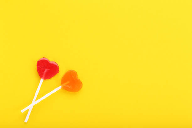 istock Heart shaped lollipops on yellow background 1127538339