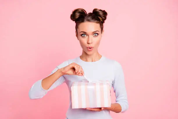 Photo of Portrait of her she nice attractive lovely sweet winsome glamorous cheerful glad girl holding in hands opening bow ribbon box isolated over pink pastel background