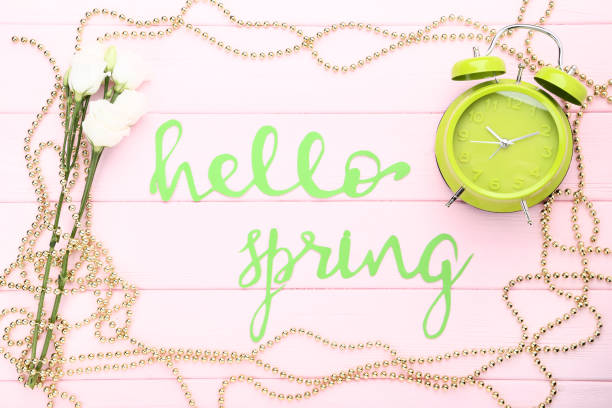 istock Lisianthus flowers with text Hello Spring and alarm clock on pink wooden table 1127541859