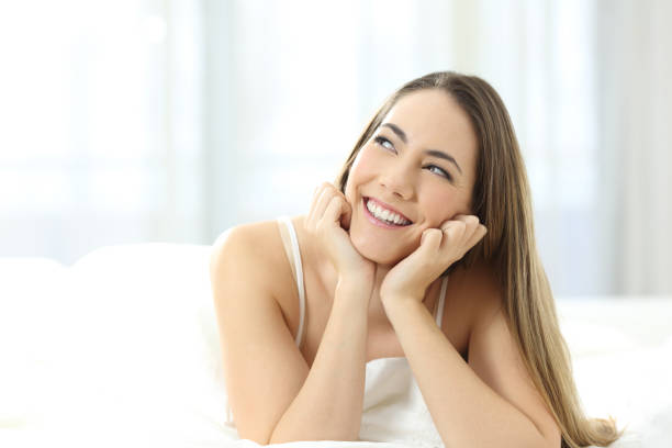 istock Happy girl dreaming looking at side on a bed 1127542891