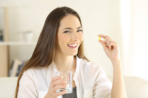 istock Happy lady holding and showing a vitamin pill 1127544006