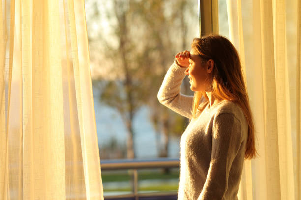 adolescente feliz exploración a través de una ventana en casa - window sun sunlight vertical fotografías e imágenes de stock