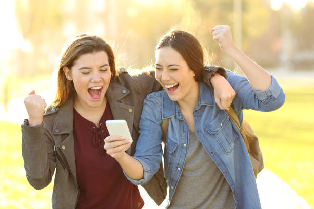 istock Excited friends watching phone content in a park 1127544285