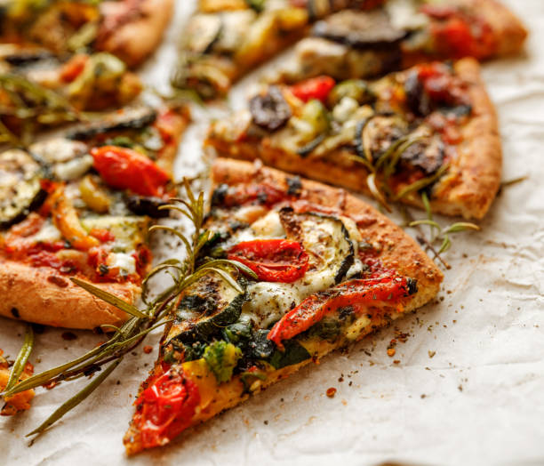 Vegetarian pizza with addition grilled vegetables and aromatic herbs Vegetarian pizza with addition grilled vegetables and aromatic herbs, divided into portions serving size photos stock pictures, royalty-free photos & images