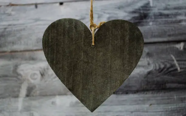 Big dark wooden heart on the dark wooden background. Close up and big space for your sign