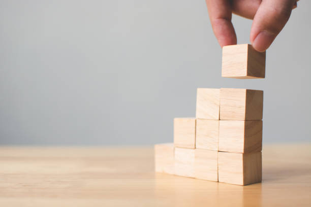 mão, organizando o empilhamento com mesa de madeira em cima do bloco de madeira. conceito de negócios para o processo de crescimento sucesso - teamwork block development working - fotografias e filmes do acervo