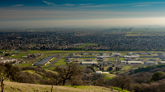 Panoramic view Vacaville and the state prison from the Lagoon Valley Park, California, USA, featuring the chaparral in the winter with green grass, and hazy sky