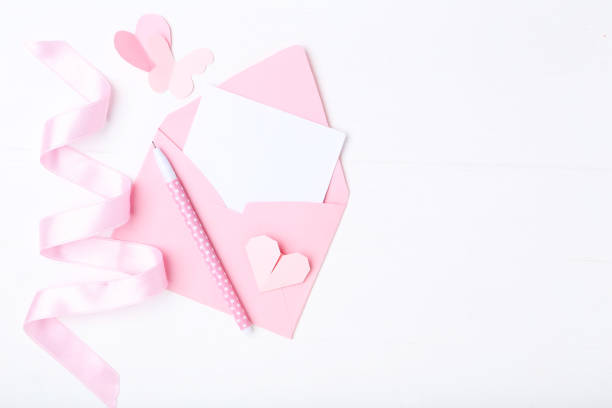 istock Pink paper hearts with envelope and pen on white background 1127547579