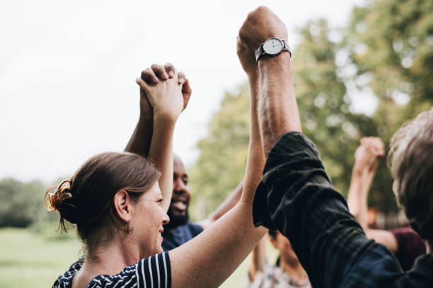istock Happy diverse people holding hands in the park 1127548623