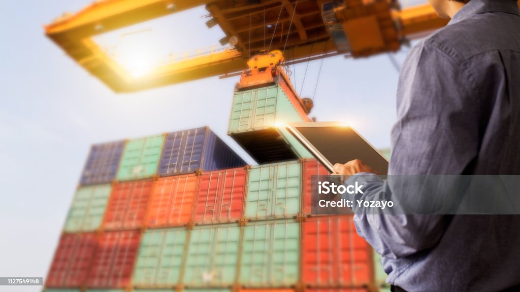 Business Logistics concept, Businessman manager using tablet check and control of Container Cargo ship with working crane bridge. Industry 4.0 concept Freight Transportation Stock Photo