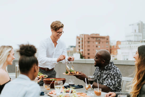 istock Man serving his friends salad at a rooftop party 1127549200