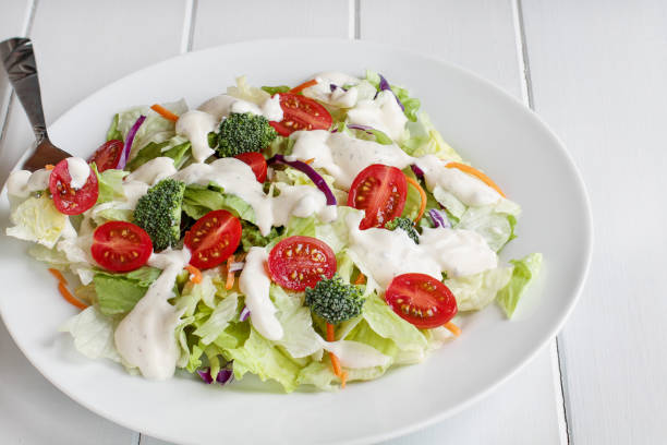 Fresh salad with buttermilk ranch dressing Plate of homemade fresh salad with buttermilk ranch dressing, tomatoes, broccoli, cabbage and carrots served over a white wooden table. House Salad. ranch dressing stock pictures, royalty-free photos & images