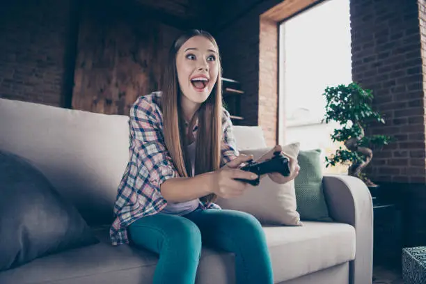 Low angle view photo portrait of cheerful ecstatic excited enthusiastic she her hipster teen girl using holding controller in hands playing wireless computer videogames