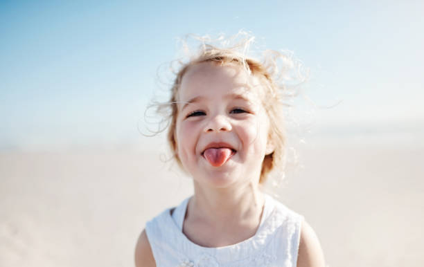 Portrait of an adorable little girl playfully sticking out her tongue at the beach