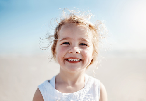 Close-up portrait of cute little girl smiling at camera on sunny summer da