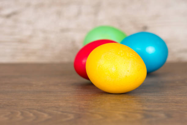 istock red, yellow, green and blue easter eggs on wooden table 1127556383