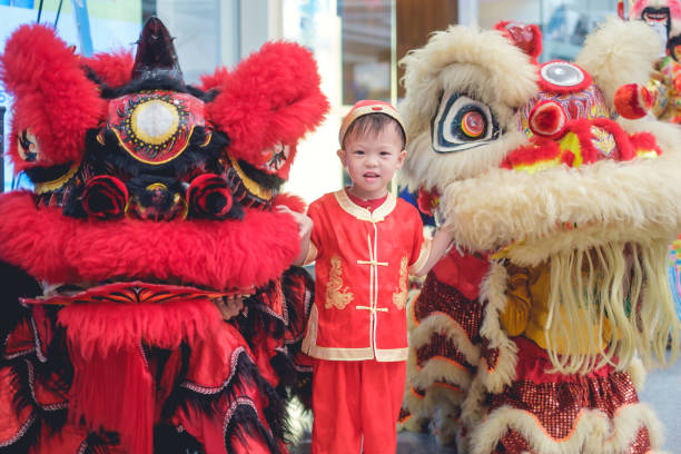 bonito sorridente 2-3 anos de idade da criança asiática bebê menino criança em traje vermelho chinês tradicional comemorando o ano novo chinês com a dança do leão chinês - chinese ethnicity chinese culture china 2 3 years - fotografias e filmes do acervo