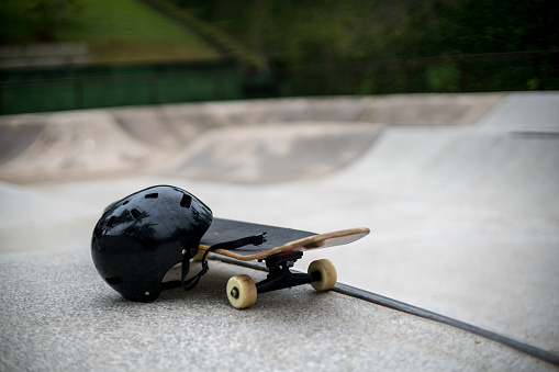 Skateboard and safety helmet on a skate park ready to ride