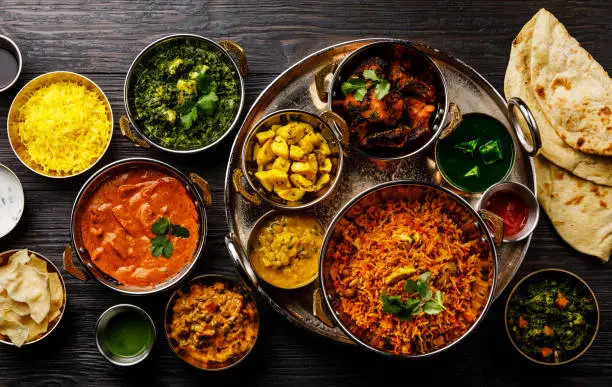 Indian food Curry butter chicken, Palak Paneer, Chiken Tikka, Biryani, Vegetable Curry, Papad, Dal, Palak Sabji, Jira Alu, Rice with Saffron on dark background