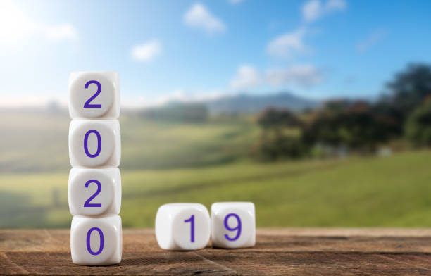 Blocks spelling 2020 on wooden table with sunlit landscape in background