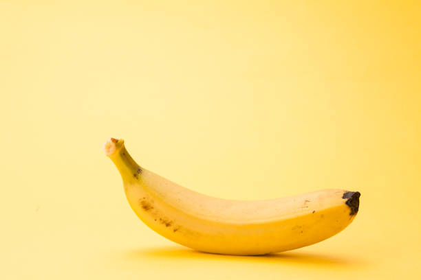 istock Single banana isolated on yellow background 1127564568