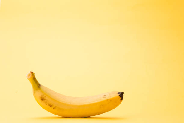 istock Single banana isolated on yellow background 1127564575