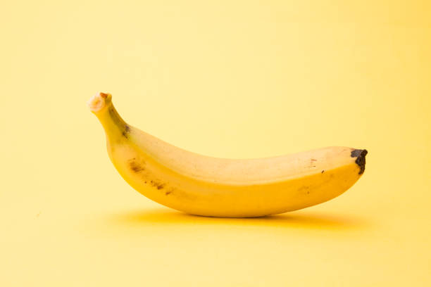 istock Single banana isolated on yellow background 1127564580