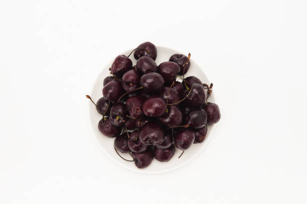 istock A bunch of cherries in a white plate on a yellow background 1127564674