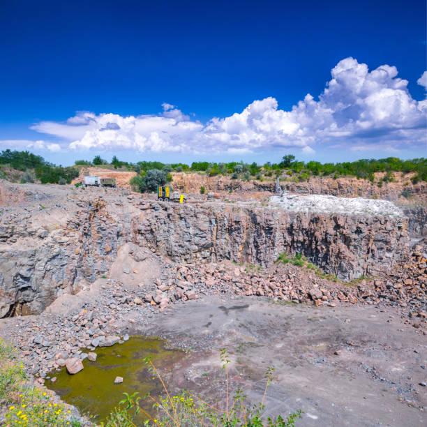 istock Spectacular view of quarry open pit mining of granite stone. Process production stone and gravel. Surface drill rig and other quarry mining equipment. Groundwater in the quarry. 1127565601