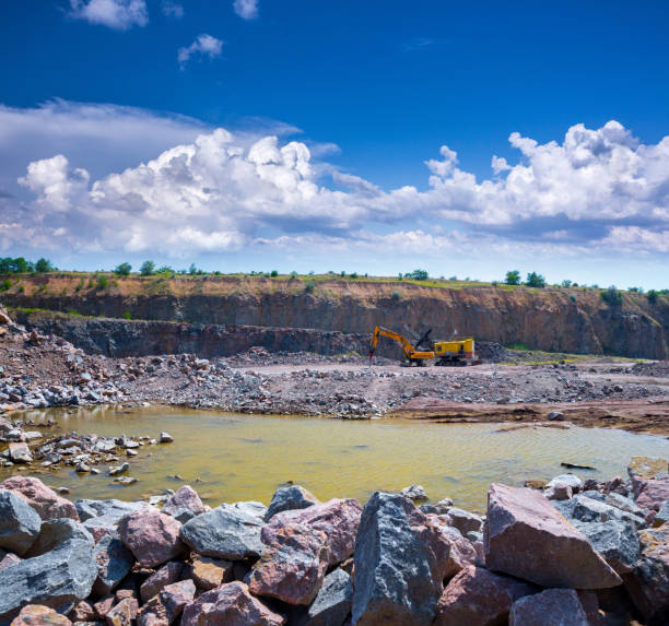 istock Spectacular panoramic view of quarry open pit mining of granite stone. Process production stone and gravel. Quarry mining equipment. A large tracked excavator and pneumatic hammer. 1127565974