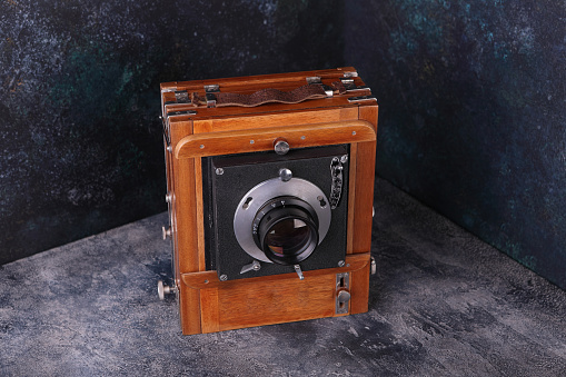 Vintage wooden camera with shutter on a cement background. The old studio camera for using plates.