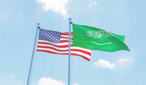 istock Saudi Arabia and USA, two flags waving against blue sky 1127568055
