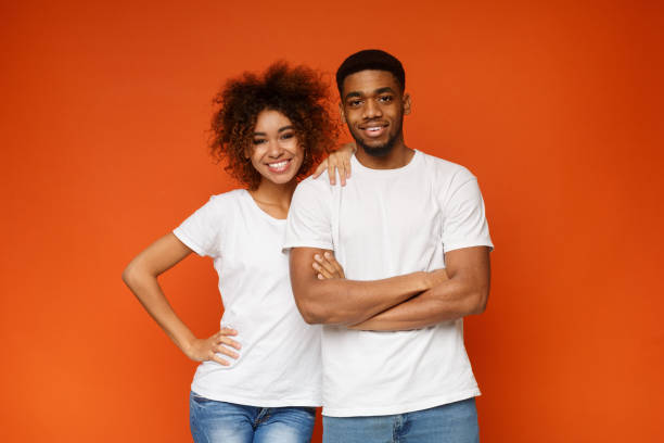 istock Young african-american couple posing on orange background 1127568128