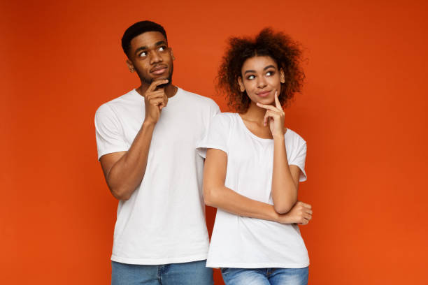 istock Young couple day dreaming on orange background 1127568131
