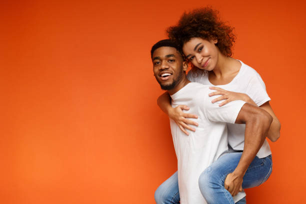 istock African-american couple having fun on orange background 1127568133