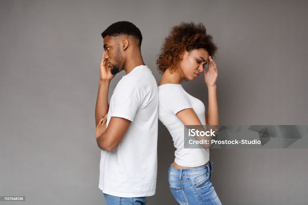 Upset couple standing back to back on gray background Break up, relationship problems. Unhappy african-american man and woman standing back to back on gray background, copy space Couple - Relationship Stock Photo