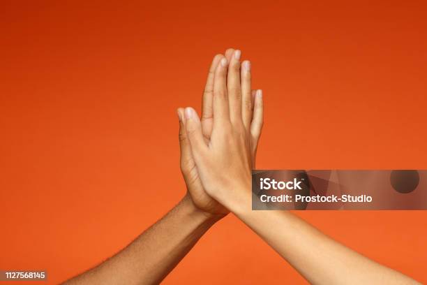Hombre Y Mujer Saludándose Con Cinco Altos Foto de stock y más banco de imágenes de Choque de manos en el aire - Choque de manos en el aire, Naranja - Color, Amistad
