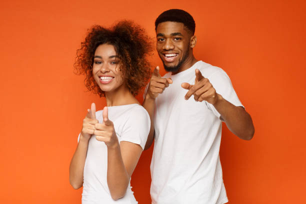istock Joyful young couple pointing fingers at camera 1127568158
