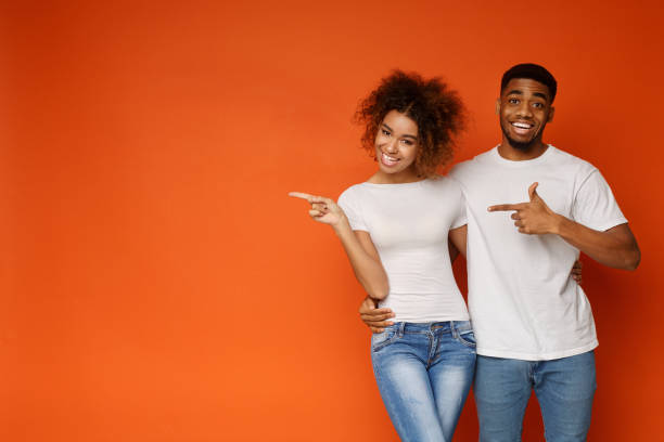 African-american man and woman point at empty space