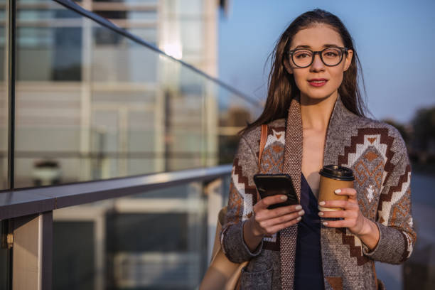 istock Pretty woman using smart phone and holding coffee 1127568254