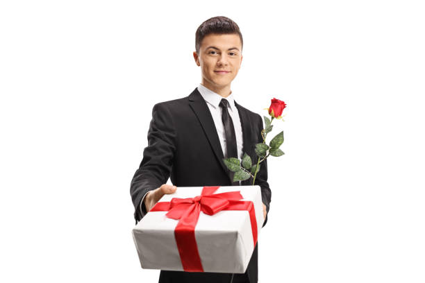 istock Handsome young man in a suit giving a present and a red rose 1127568558